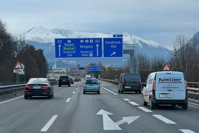 Motorway in the Inn valley approaching Innsbruck, with signs towards the Brenner and snow-capped peaks in the background